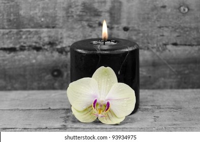 A Black Candle And An Orchid Flower