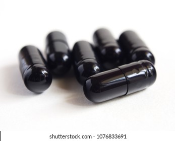 Black capsules isolated on white background. Pills can contain any medicine, herbal or chemical.