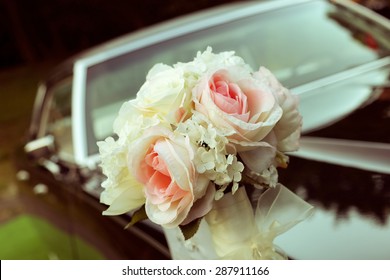 Black car with a delicate bouquet of roses. Wedding car decoration. A special day, wedding, holiday. A bouquet of artificial flowers. Floristry, decoration of the wedding.