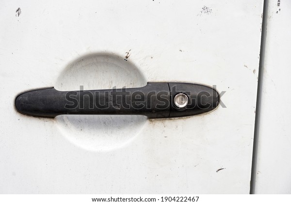 Black\
car door handle on old dirty scratched white\
paint