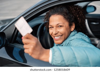 Black car driver woman smiling showing new driver's license
