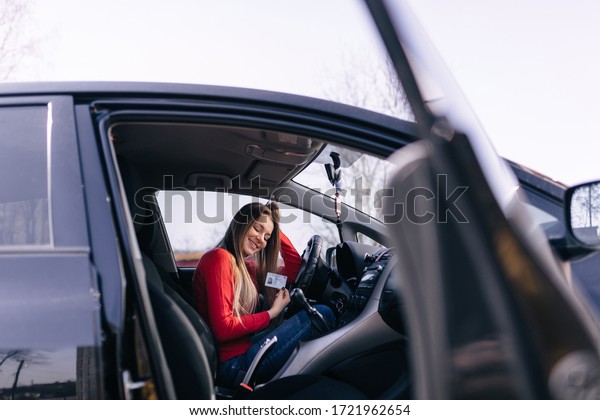 Black car driver woman smiling showing new\
driver\'s license