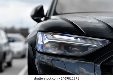 black car headlight, close up view, car dealing and manufacturing, cropped car image - Powered by Shutterstock