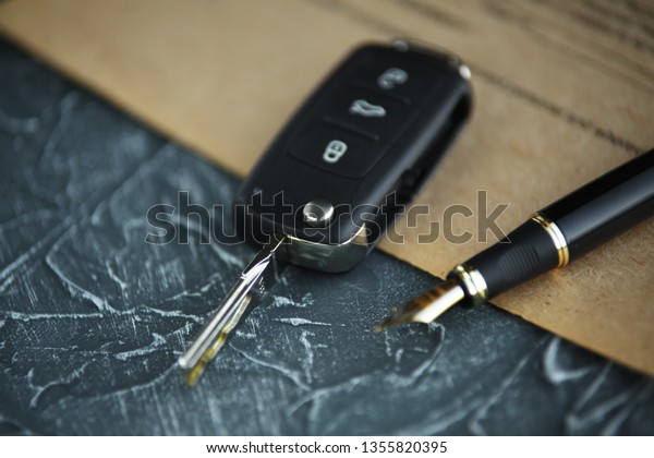 Black\
car key and money on a signed contract of car\
sale.
