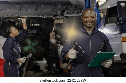 Black car mechanic man and African technician woman working in auto repair service, black mechanic man and woman workers doing car maintenance in garage, smiling African American technician concept - Powered by Shutterstock