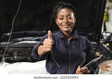 Black car mechanic woman showing thumbs up while working in auto repair shop, black female American mechanic fixing car in garage,smiling black African American woman technician doing car maintenance  - Powered by Shutterstock