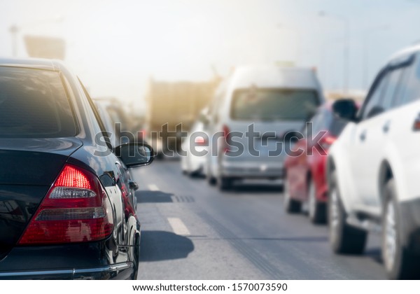 Black car and other cars stop on asphalt road.\
Traffic jam during rush hour. Keep connecting in various lenses\
orderly. And bright\
light.