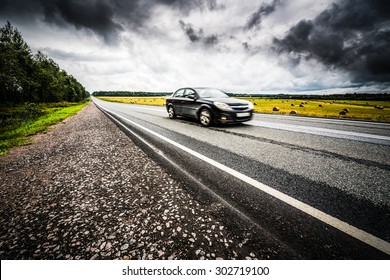 Black Car Racing On A Rural Road. View From The Side Of The Road, Image Vignetting And Hard Tones