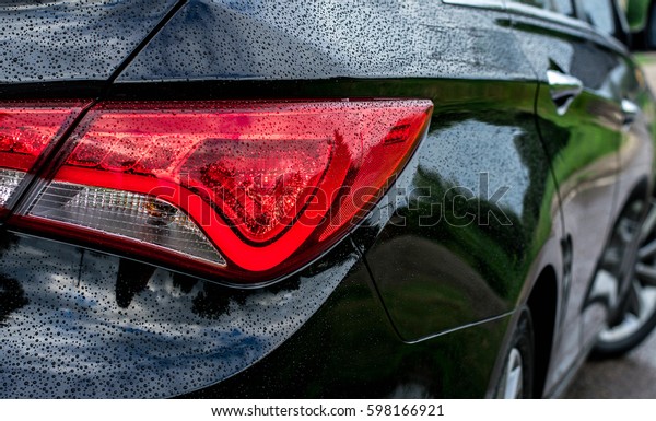 Black car with red\
brake light off headlight