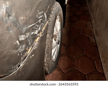black car side damage. Sharp scratches and peeling paint areas give a rough and worn look. Can be used for damage concepts, problems, or repair needs. The dark background adds drama.