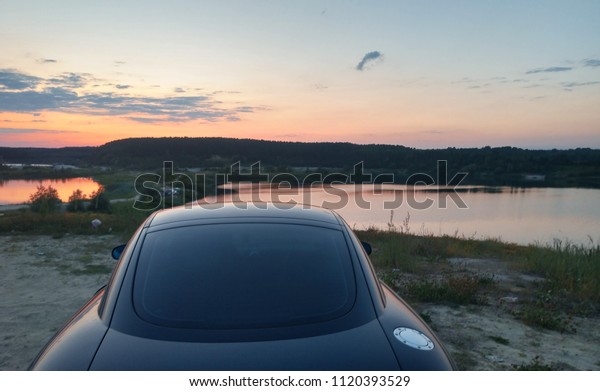 Black car and sunset on the\
lake.
