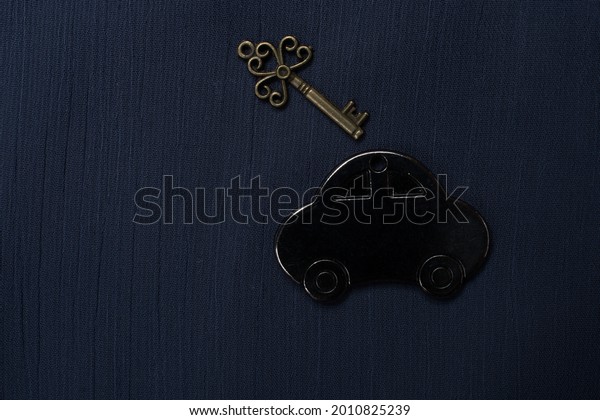 A black car tag and vintage key isolated on a\
blue background