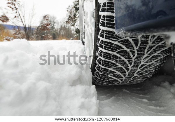 Black car tyre with a trail on the white snow in\
the winter forest