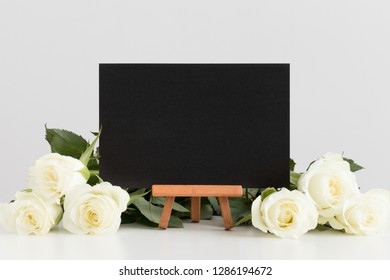 Black card mockup with roses on a white table.