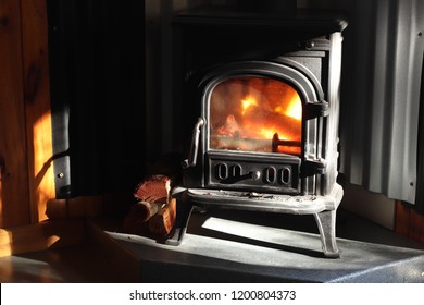 A black cast iron fire place with wood burning inside of it. Keeping warm concept image. 