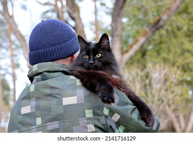 A Black Cat Looking Over Mans Shoulder