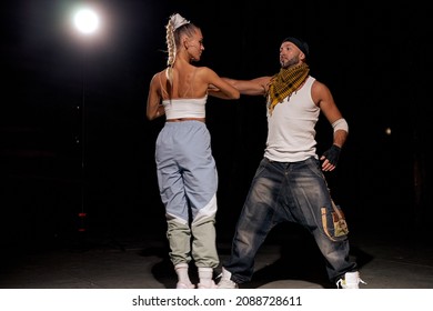 Black And Caucasian Couple Dancing Contemporary Dance In Studio.black Background. Dance Lessons. Hip Hop Dance Performance On Stage. Man, Woman Giving Performance Together, Dancing In Hip Hop Style