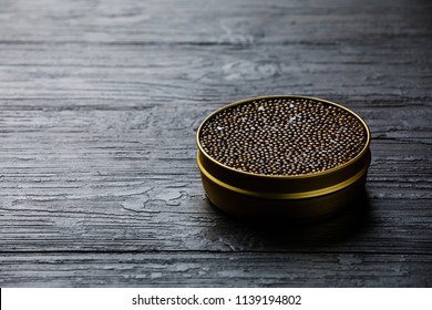 Black caviar in can on black wooden background copy space