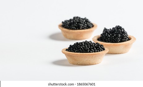 
black caviar on a white plate. tartlet with black caviar. snack.
