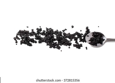 black caviar and spoon isolated on white background. the eggs of caviar scattered on the surface. flat lay, top view