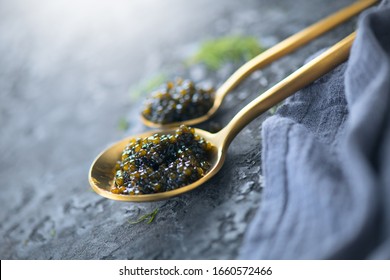 Black Caviar in a spoon on dark background. High quality real natural sturgeon black caviar close-up. Delicatessen. Texture of expensive luxury caviar. Food Backdrop.