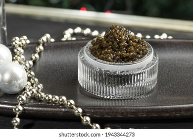 Black caviar. Black sturgeon caviar in a ceramic bowl and silver beads on a silver tray. Christmas and New Year background