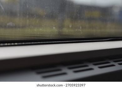 Black ceramic dot pattern on a vehicle window glass with vents in the foreground and blurred view