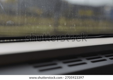 Black ceramic dot pattern on a vehicle window glass with vents in the foreground and blurred view