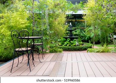 Black chair in wood patio at green garden with fountain in house. Outdoor garden.