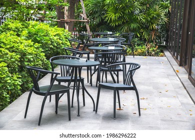 Black chairs and round tables set in the garden at a cafe, outdoor zone in Thailand, outside seating. - Powered by Shutterstock