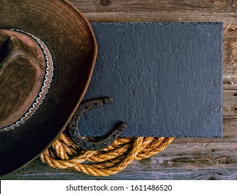Black chalk board lasso horseshoe and traditional cowboy hat on wooden background