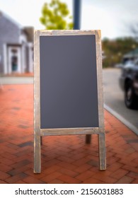 Black Chalkboard Advertising Wooden Framed Sign Standing On The Red Brick Street