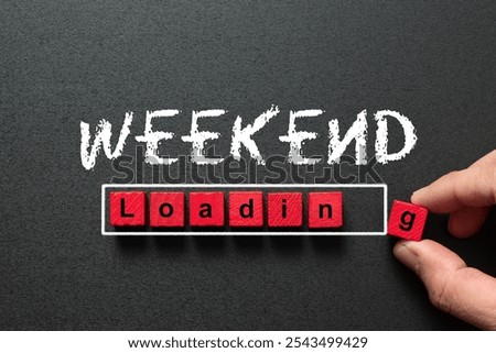 Black chalkboard with a concept of weekend loading bar from red wooden blocks with the hand putting in the last block