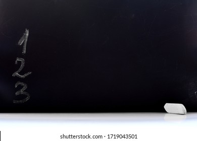 Black chalkboard with series of numbers to do list and piece of chalk on white desk. Mock up business concept background with copy space