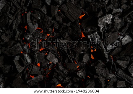 Black charcoal with red streaks of heat. Black textured background.