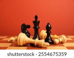 Black chess pieces among other fallen white ones on chessboard, closeup. Competition concept