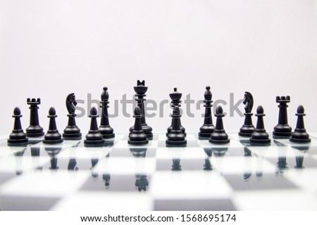 black chess pieces on a glossy chessboard on a white background