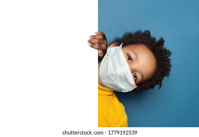 Black child boy in medical protective face mask holding white empty paper singbard - Powered by Shutterstock