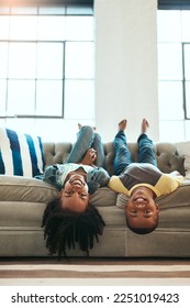 Black children, siblings and relax on living room sofa lying upside down with smile for fun time together at home. Happy African American kids relaxing, playing and smiling on couch at the house