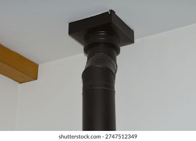 Black chimney pipe connected to ceiling in modern interior home