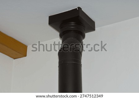 Black chimney pipe connected to ceiling in modern interior home