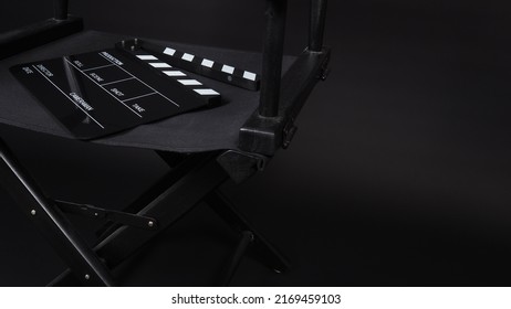 Black Clapperboard Or Clap Board Or Movie Slate With Director Chair Use In Video Production ,film, Cinema Industry On Black Background.