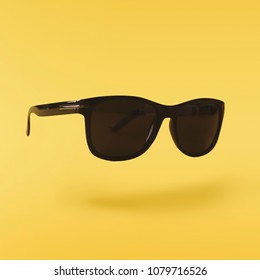 Black Classic Sunglasses Hovers In The Air On Yellowbackground. Design Mockup. Minimal Concept