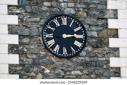 The black clock face with gold numbers on a stone wall - Powered by Shutterstock