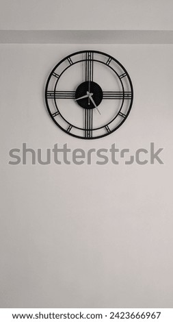 A  black clock in white plain wall background looking very simple and beautiful.