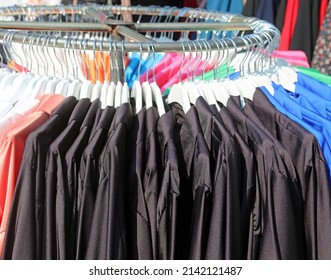 Black Clothes And Aprons For Kindergarten And Elementary School Hanging On The Coat Rack In A Trendy Clothing Stall Of The Outdoor Market