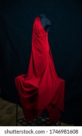 Black clothing mannequin dummy with red drape folding down in the studio with black background
