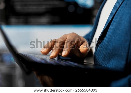 Black coder focused on programming with laptop at a digital workstation, writing binary code on terminal window for automation. Professional tech career in data science. Close up.