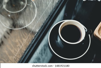 Black coffee cup on table in cafe restaurant near window in garden when raining in garden outside shop,Food and drink concept,Leisure lifestyle.