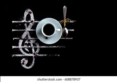 Black coffee in a cup with a spoon on a black background as a concept of musical notes